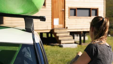 woman removing the kayak from car roof rack 4k