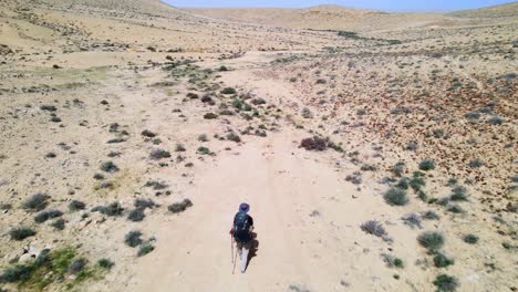 aerial orbit and fly over of hiker on desert trail showing wilderness landscape on sunny day with blue sky