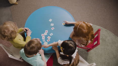 close-up van leerlingen die aan een rond bureau zitten en spelen met letters van het alfabet in een montessorischool