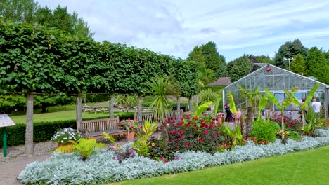 daylight camera pan reveals vibrant flower beds, manicured hedges, and greenhouse structures in a lush botanical garden setting in durham, england
