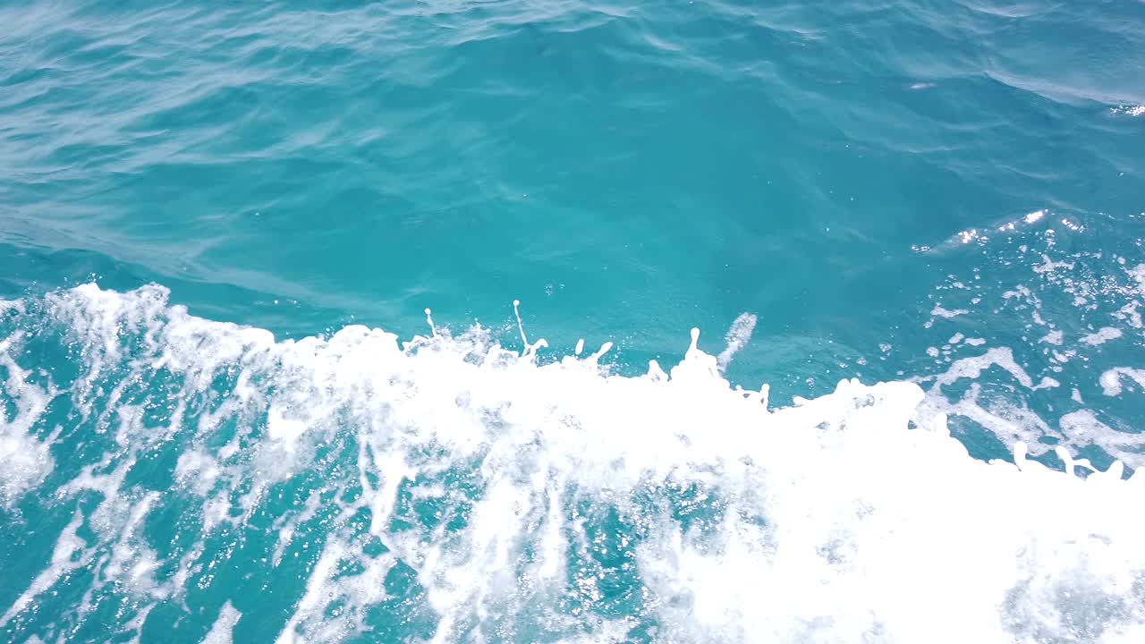 water splashes on the side of the boat while sailing on clear seawater on a sunny day in Maldives