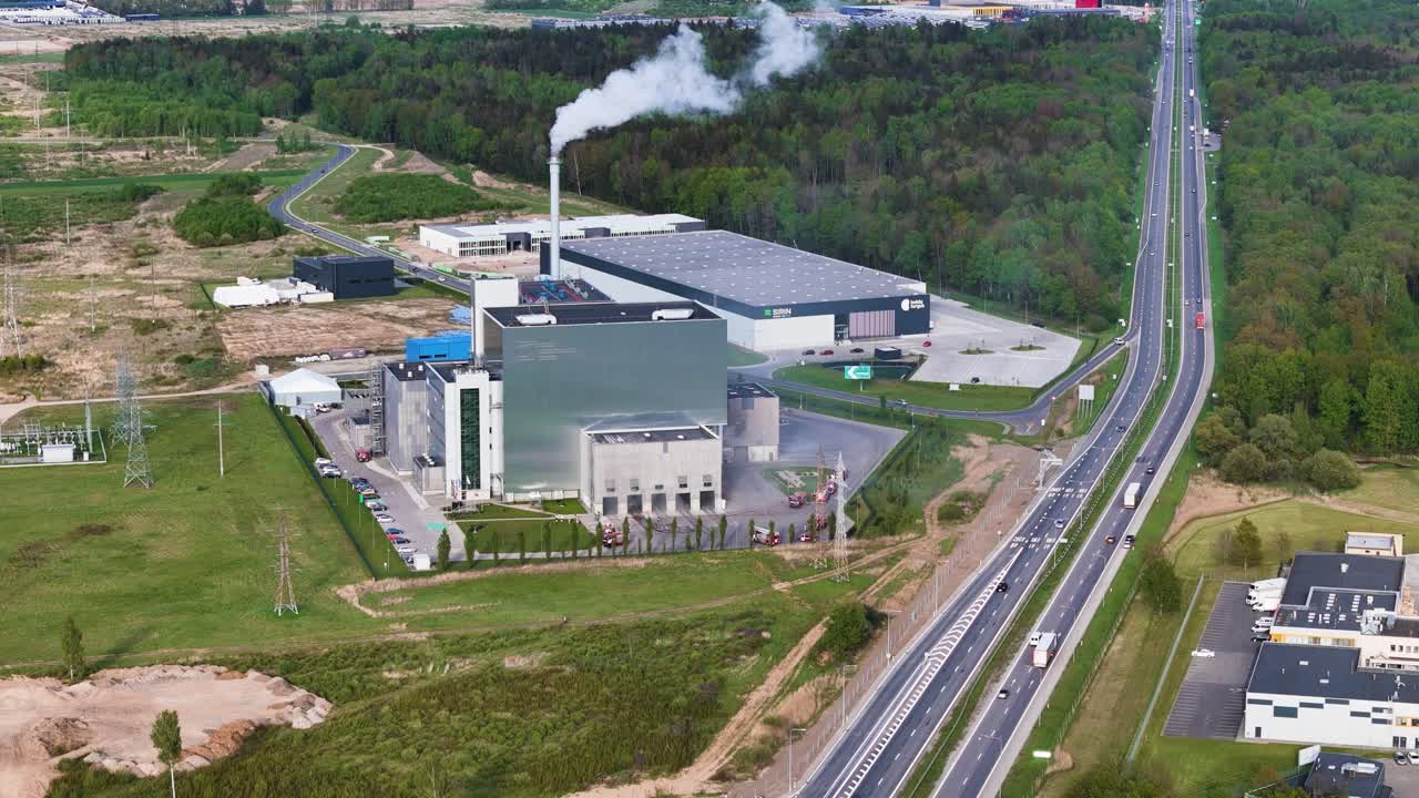 Aerial flyover of a large-scale fire response at the Kaunas energy plant, with visible smoke and rescue activity.