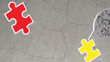 animation of green, yellow and red puzzle pieces falling over model of human head on grey background