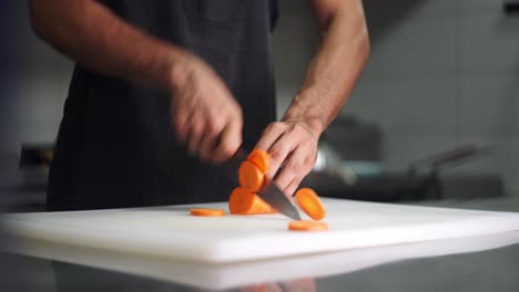 Slow motion close up view of a Chef slicing orange carrots under cinematic and beautiful atmosphere