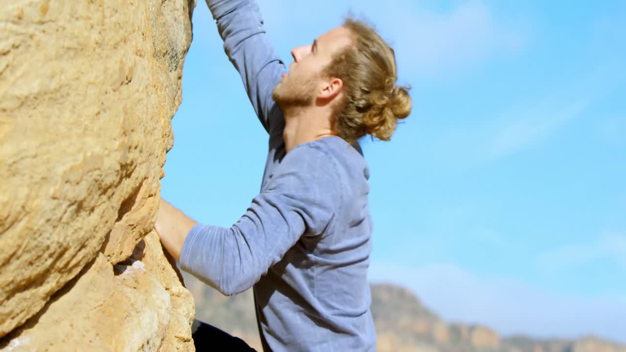 excursionista masculino escalando una montaña rocosa en el campo 4k