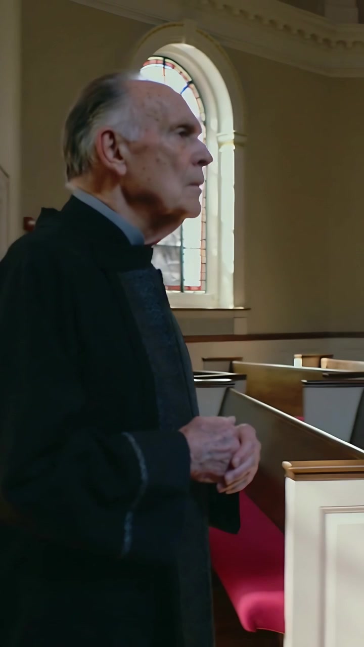 Vídeo vertical: Padre de batina entrando na igreja, caminhando pelo corredor, parando para orar nos bancos, com espaço para texto.