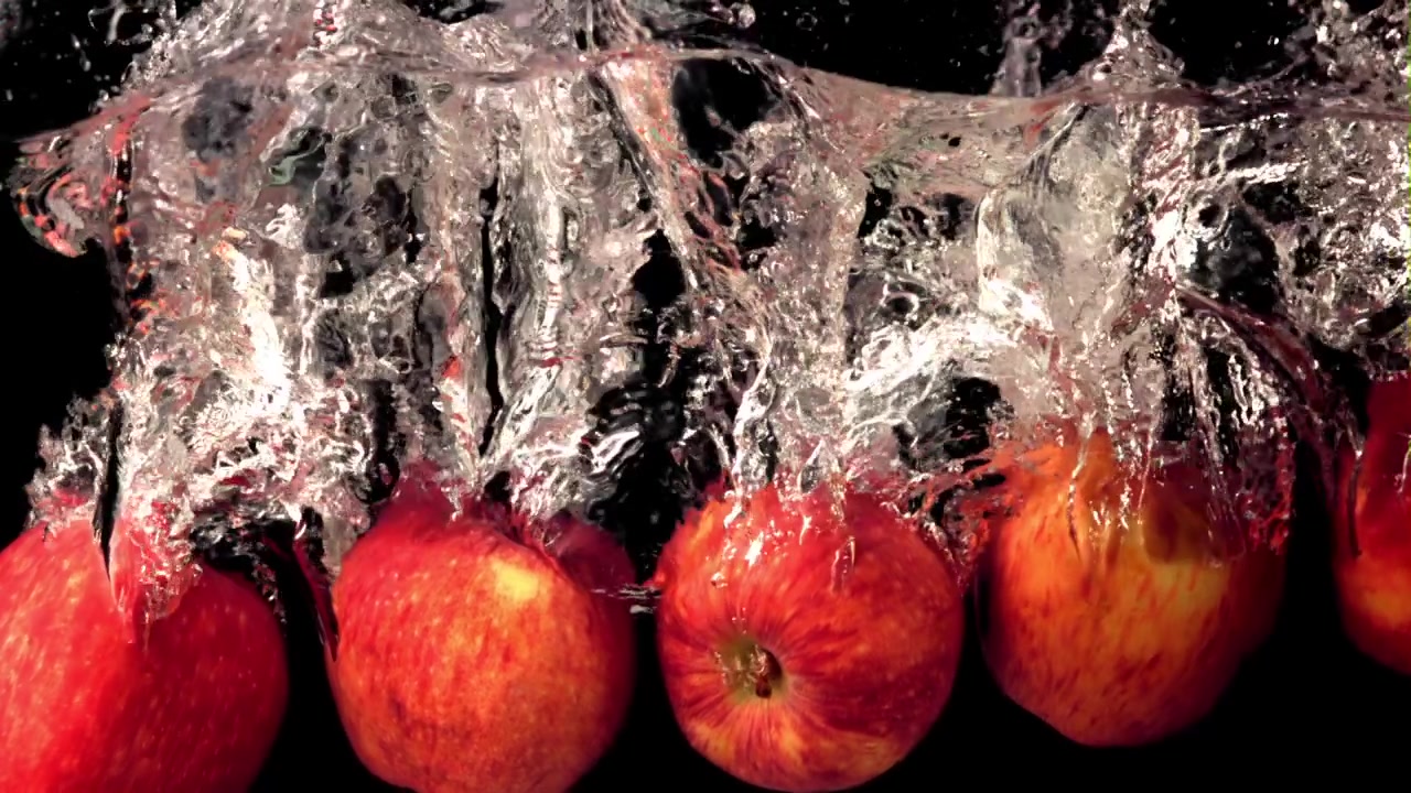 Mele rosse che schizzano nell'acqua al rallentatore.