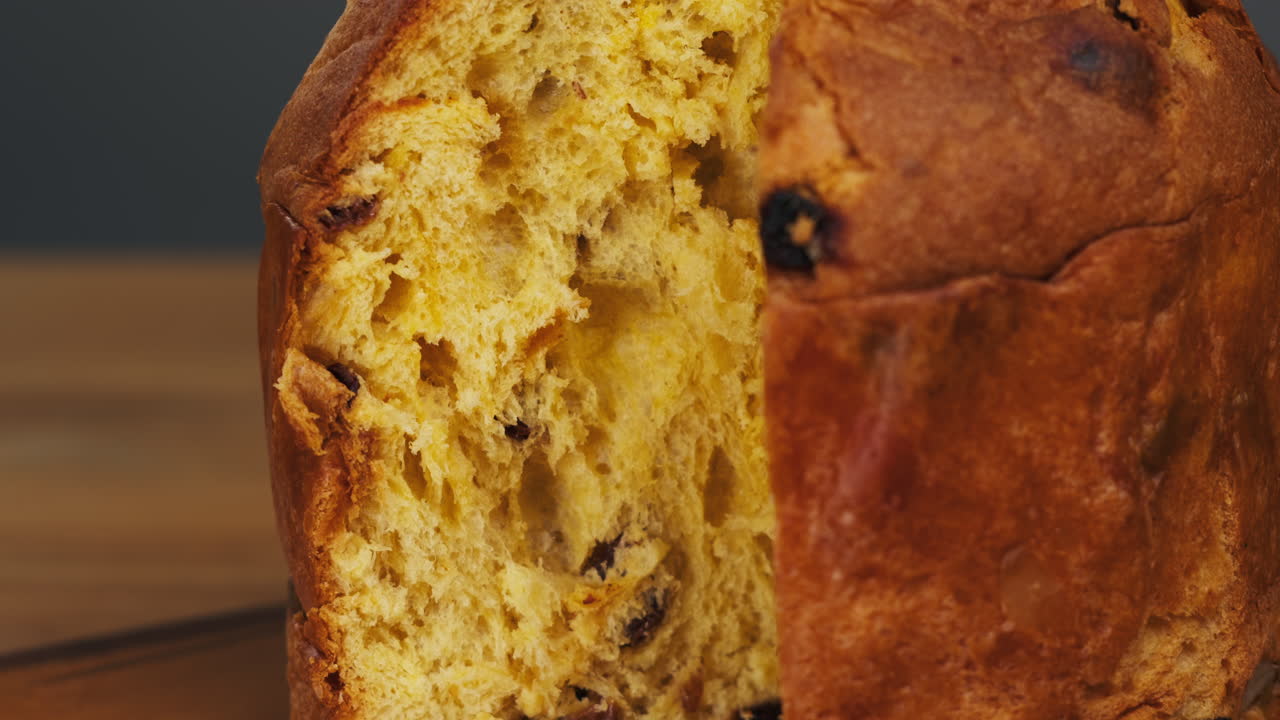 Traditional English Christmas cake tied with a jute thread on the black background. Italian classic Panettone .Pastry Chef sprinkles powdered sugar through a sieve on the fruit Easter cake with raisins. High quality 4k footage