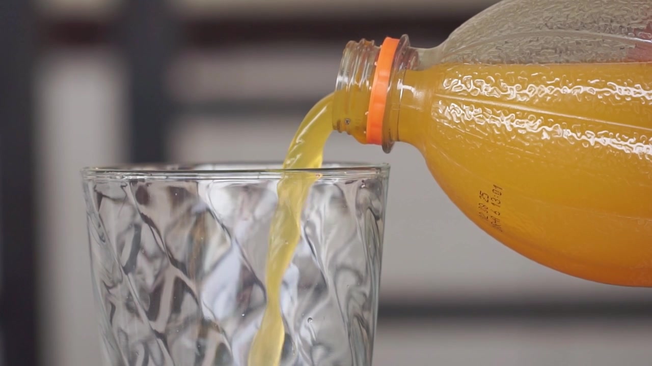Succo d'arancia fresco versato da una bottiglia in un bicchiere. Bevanda salutare, bevanda alla vitamina C, rinfrescante bevanda agli agrumi