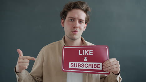 man holding sign with like and subscribe request