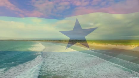 Digital-composition-of-waving-ghana-flag-against-aerial-view-of-beach-and-sea-waves