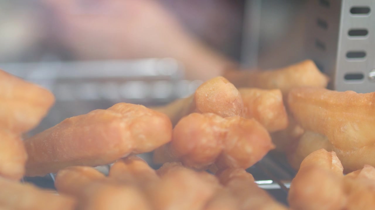Primo piano statico di bastoncini di pasta fritta asiatica croccanti che riposano su una griglia metallica