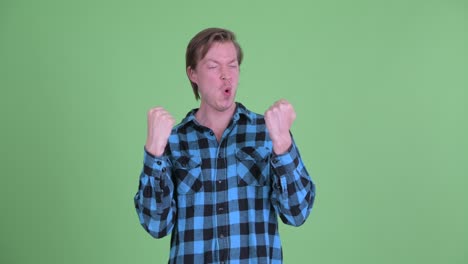 portrait of caucasian man looking excited with arms raised shot against green studio background