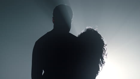 silhouette guy and girl embracing in dark space. romantic couple dancing.