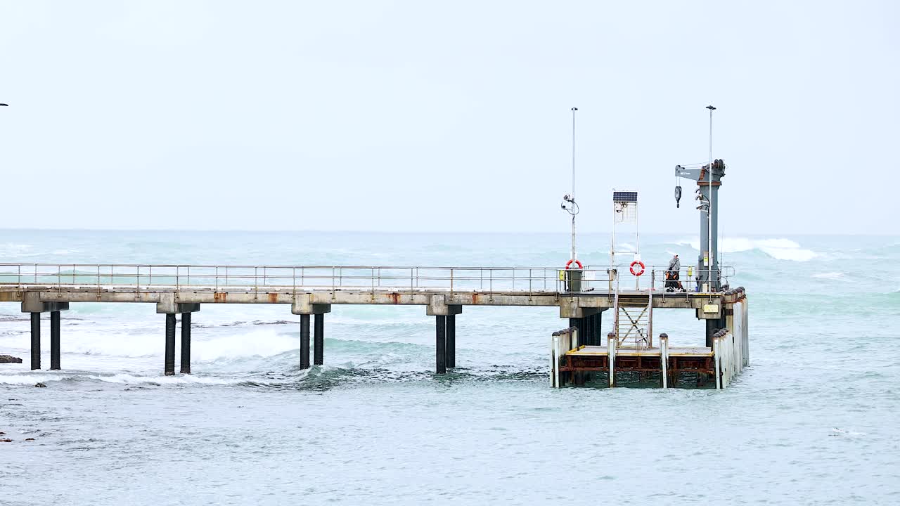A serene view of Port Campbell pier with gentle waves under soft daylight, capturing a peaceful coastal scene