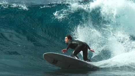slow motion telephoto of longboard surfer rising up to top and cutting back off lip of wave