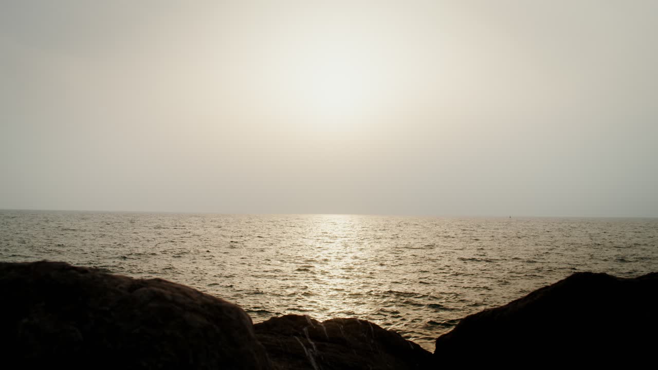 바위 해변에서 바다 위에 해가 지는 모습