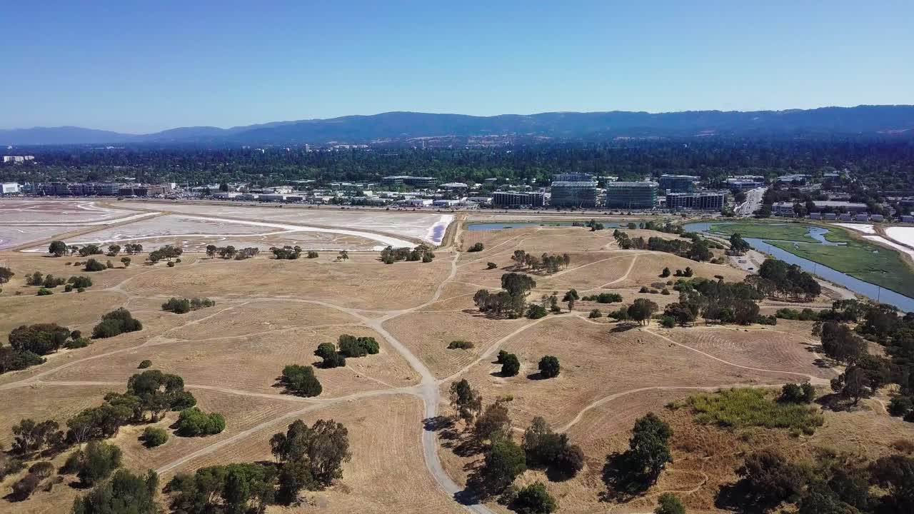 Aerial of Bedwell bayfront park in menlo park with mounatins and corporate buildings in front, silicon valley california