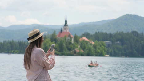 woman taking photo of lakeside church