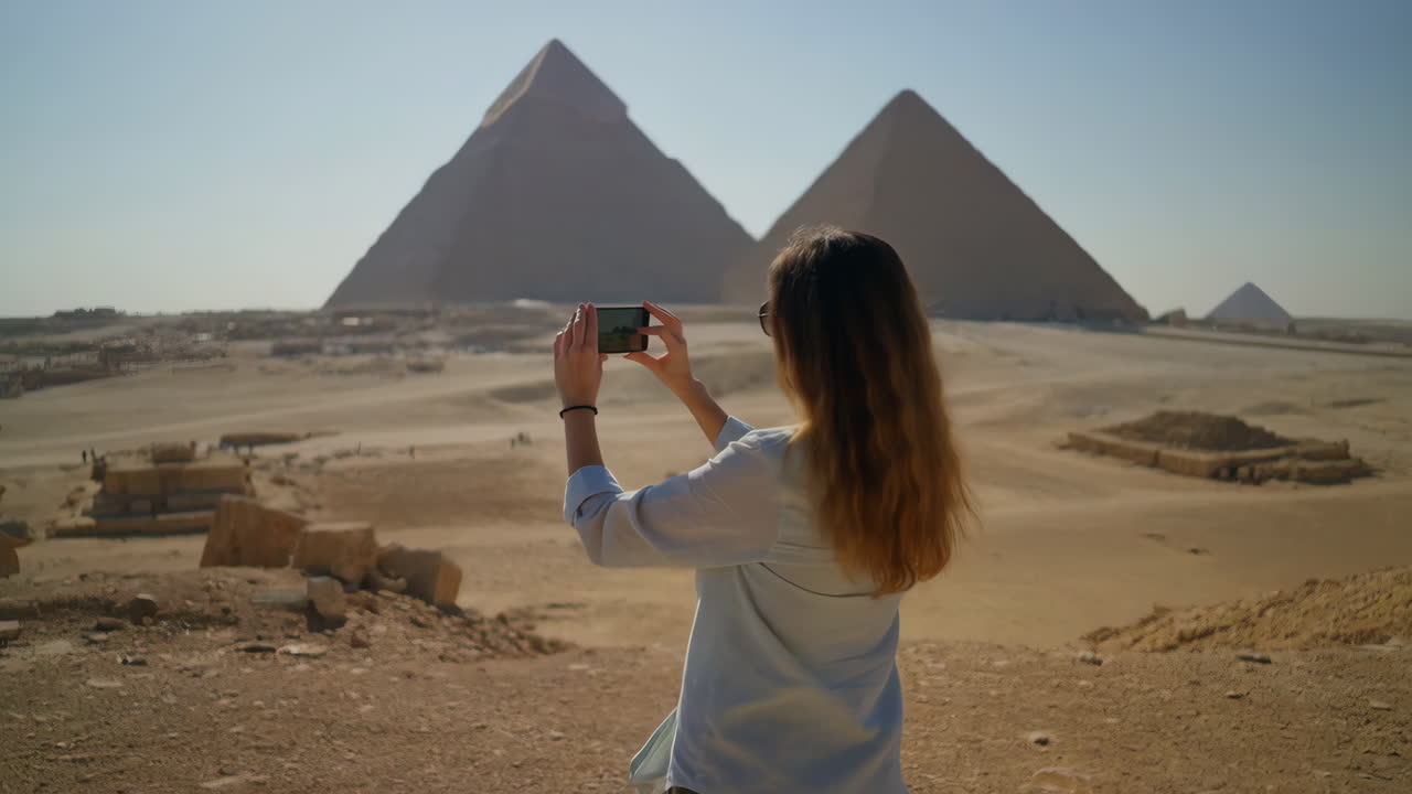 Woman taking a photo of the Giza Pyramids in Egypt