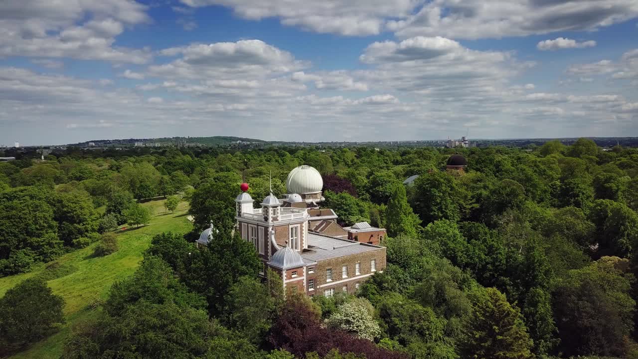 Beautiful aerial drone view of Royal Greenwich Observatory and Museum in the middle of beautiful nature and forest under scattered clouds and blue sky during daytime