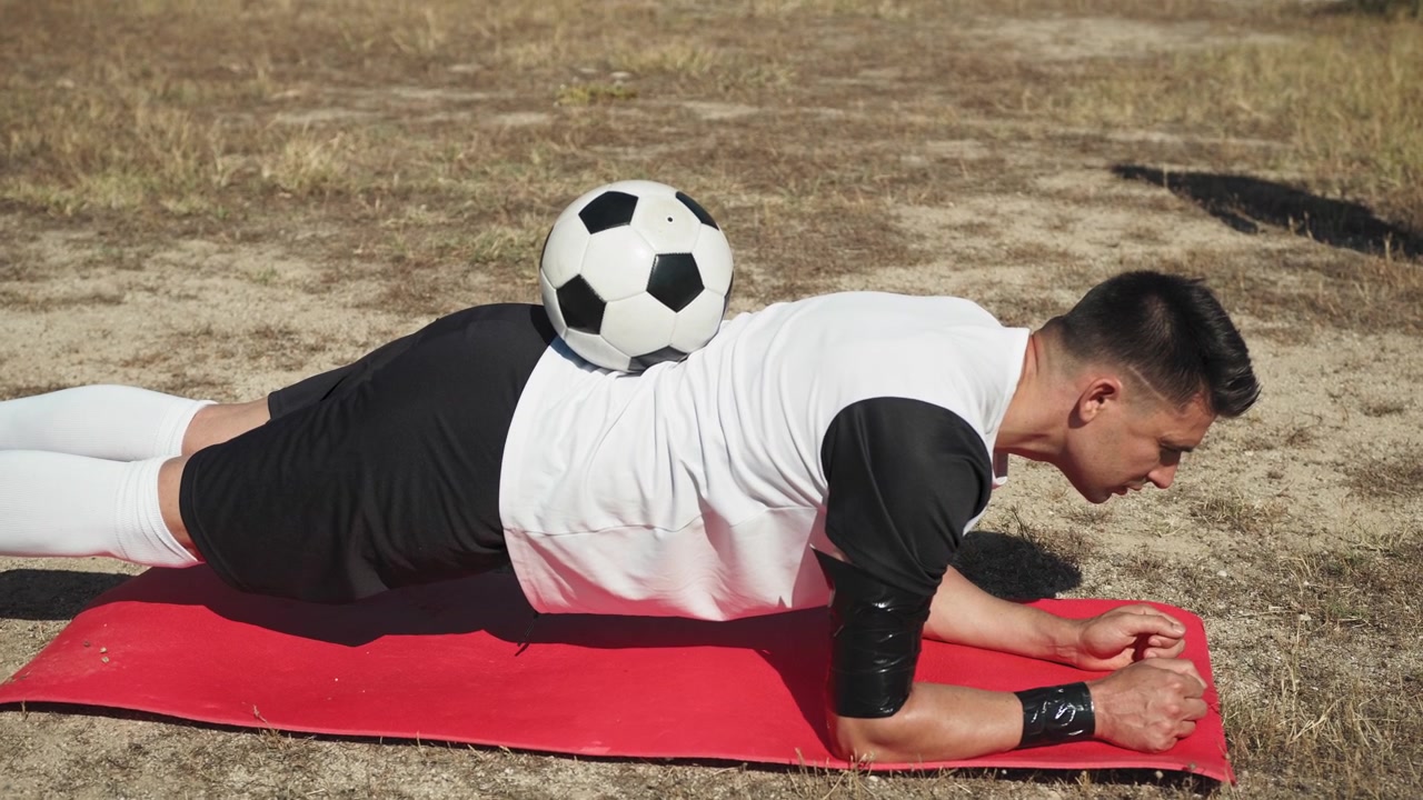 Player Doing Plank And Mantaining The Ball On The Back