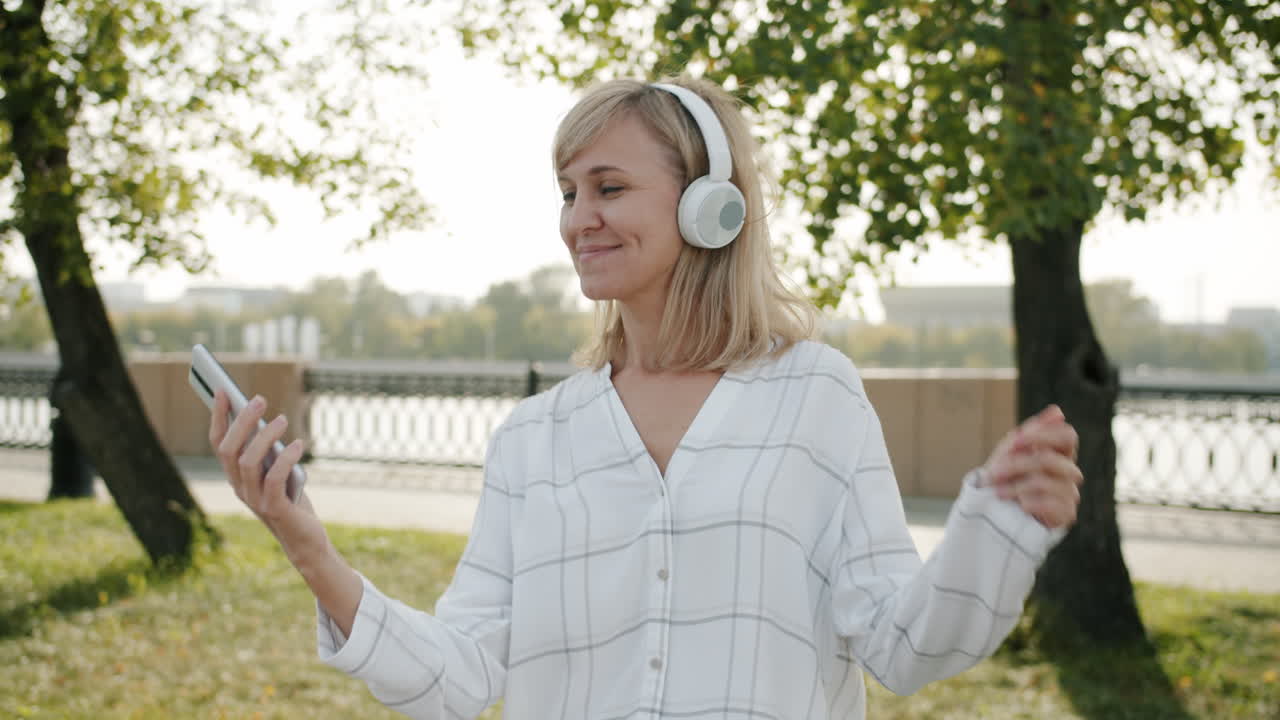 Woman listening to music and taking a selfie in a park