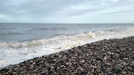 Sandige-Wellen-Stürzen-In-Zeitlupe-Auf-Den-Walisischen-Kiesstrand