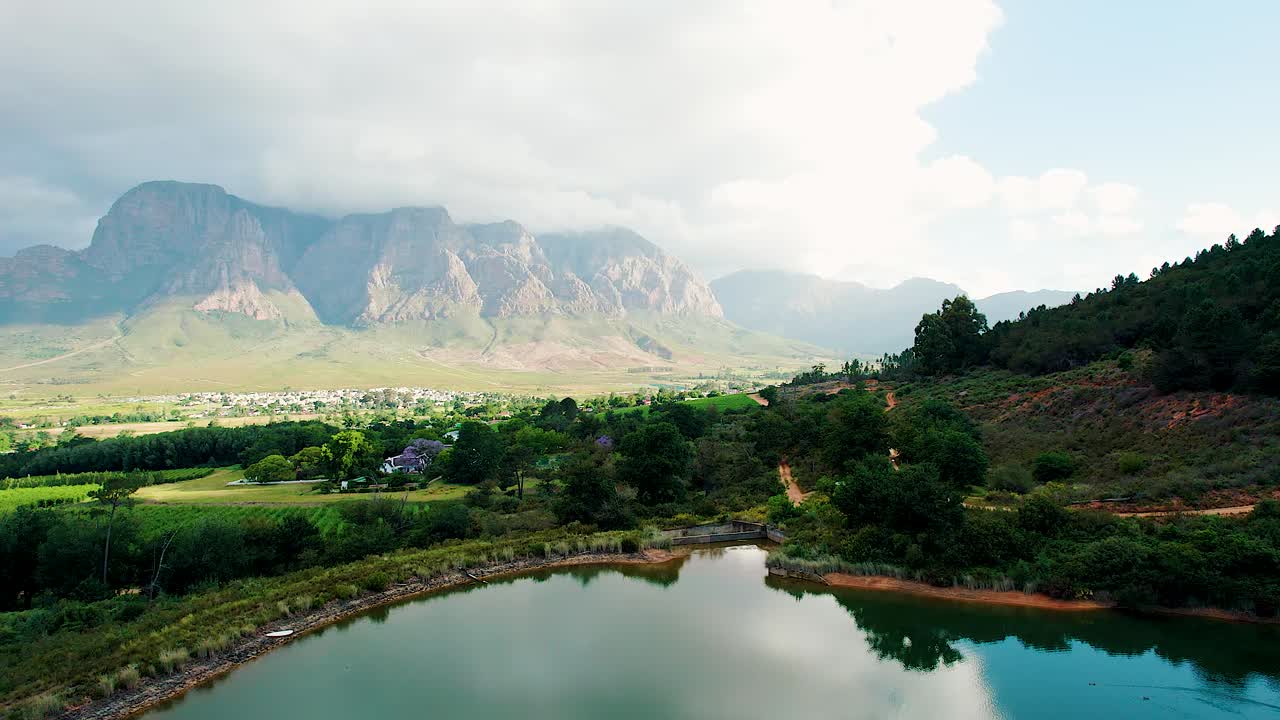 Experience South Africa's captivating nature and mountains in stunning drone footage Discover beautiful green areas, serene villas in the woods, moving clouds, and sunlit mountains and a tranquil lake