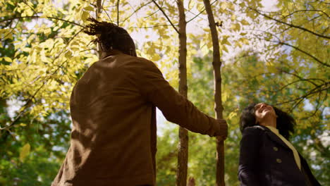 Family-enjoy-autumn-park-dancing-under-falling-leaves-in-warm-golden-sunlight.