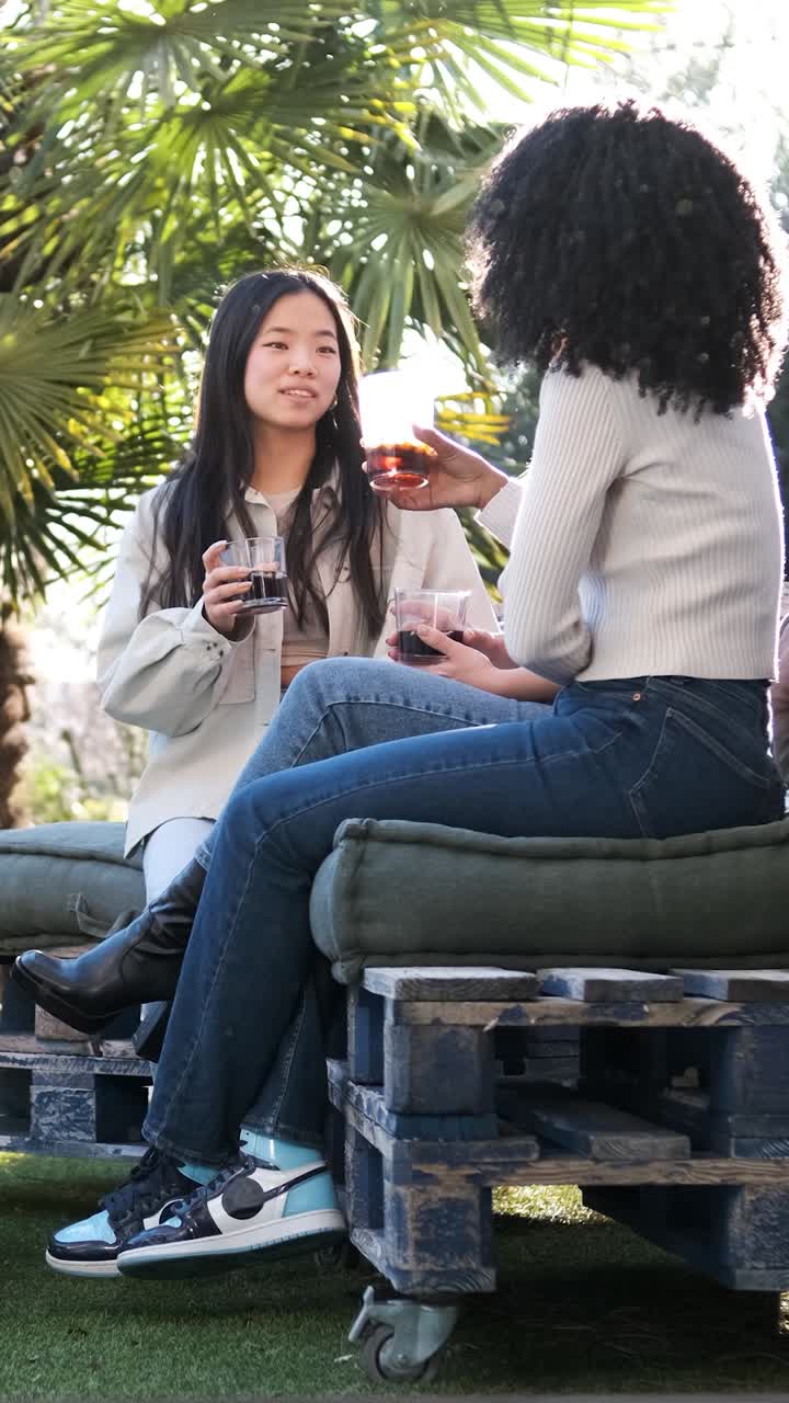 Diverse girlfriends sitting on terrace and chatting