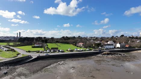 Bordeaux-Harbour-Guernsey-circling-drone-shot-on-sunny-day-with-boats-on-hardstanding-and-views-over-beach-to-St-Sampsons