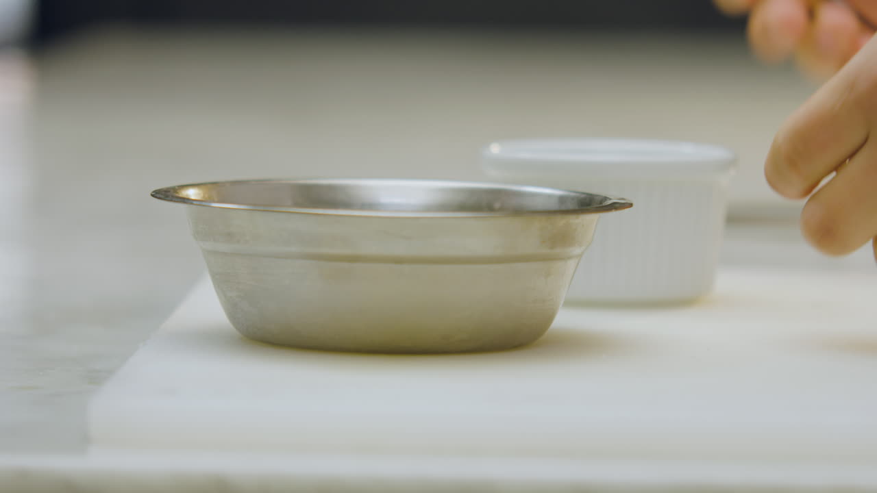 Close-up of a chef using tongs to transfer apple slices from an aluminum mold to a ceramic mold