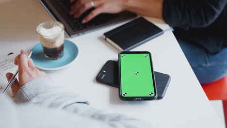 Close-Up-Of-Two-Green-Screen-Mobiles-Phone-To-Phone-Wirelessly-Charging-On-Desk