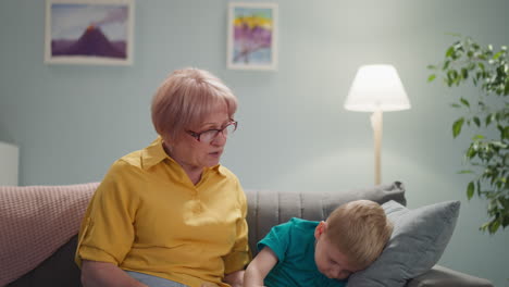 granny tries to calm down naughty grandson playing on sofa