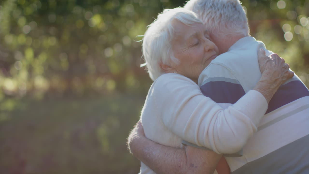 una feliz pareja caucásica se abraza en un jardín soleado, cámara lenta, espacio de copia