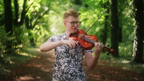 Medium-shot-of-young-man-playing-the-violin-in-beautiful-dreamy-forest