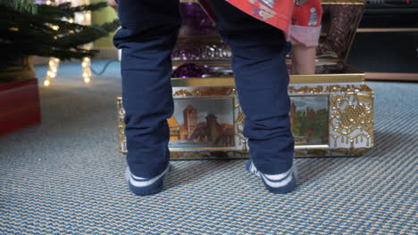 closeup of a child's feet as they spin to open a box with christmas decorations