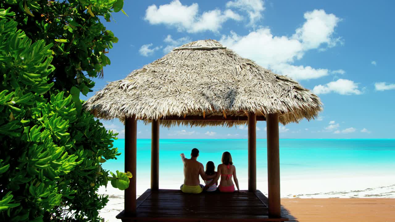 지붕 의 티키 오두막 에 앉아 있는 젊은 백인 가족