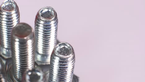 rotating group of galvanized metallic screws close-up. steinless steel bolts isolated on white background.