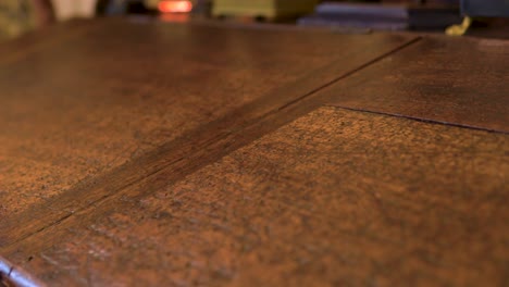 close-up-of-scratched-marked-beaten-writing-antique-table-dramatic-mysterious-slow-motion