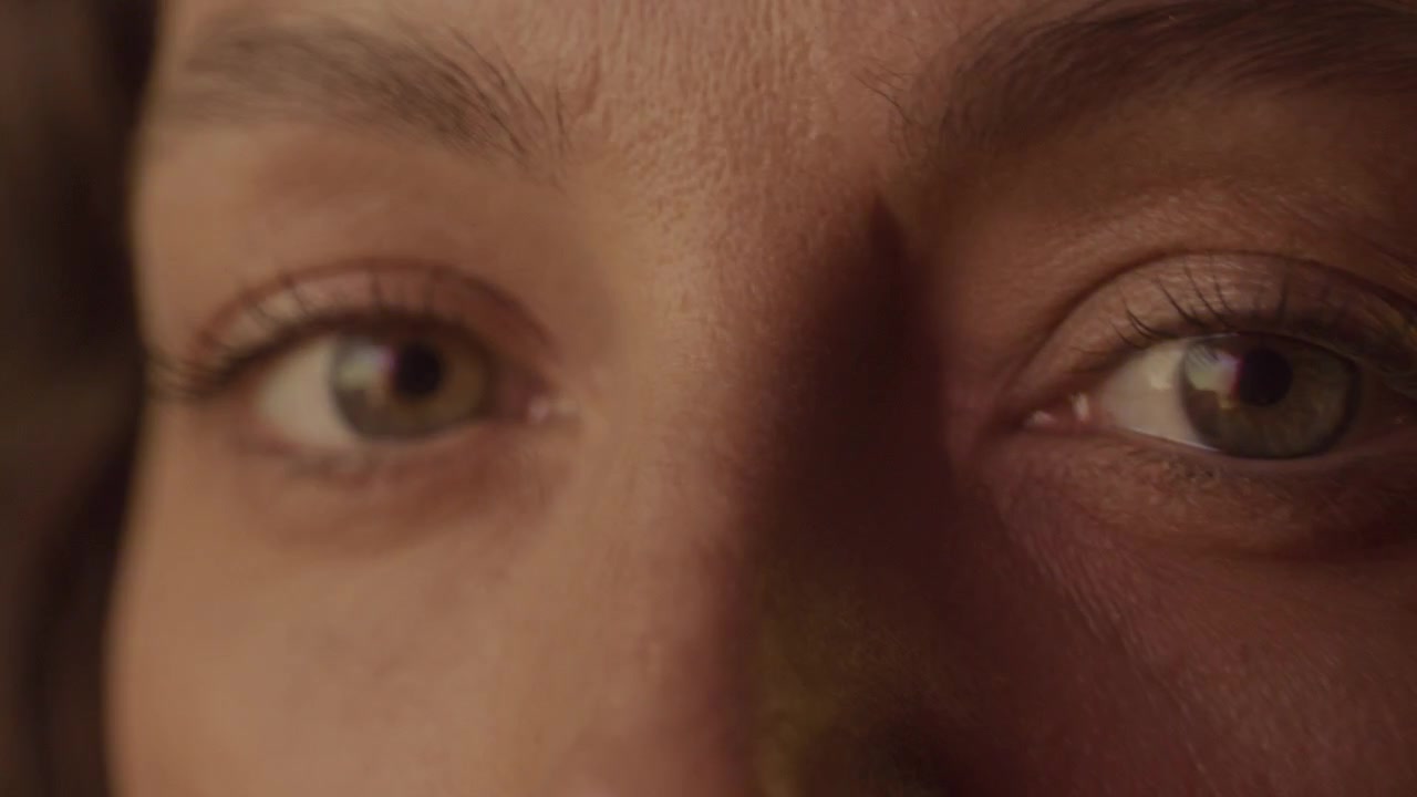 Olhos de Mulher Olhando para Longe, Depois Virando para a Câmera Sob Luz Neon Colorida