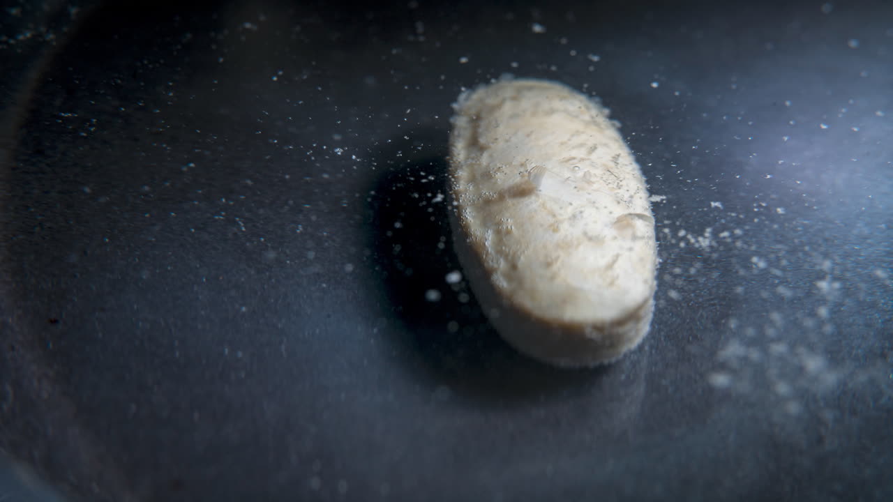 Pill dissolving in water, close-up shot of the pill breaking apart in liquid