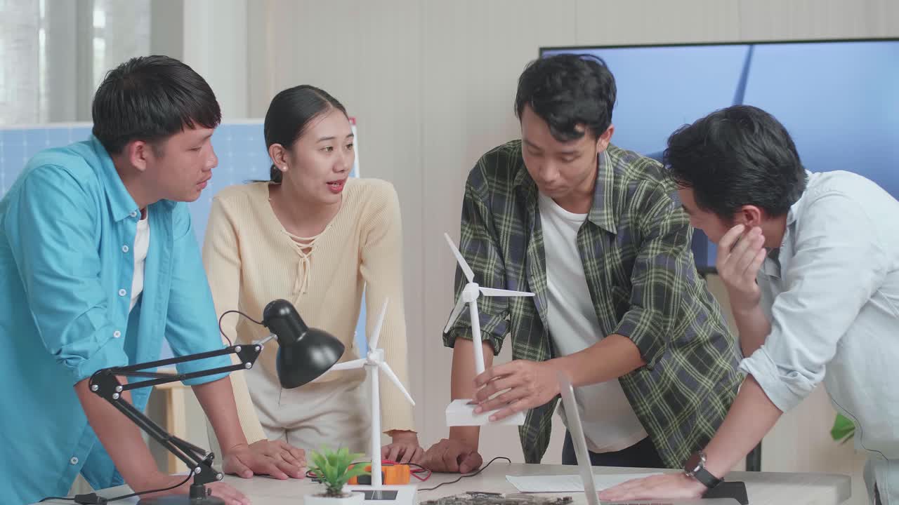 엔지니어링 그룹의 아시아인 남성과 여성이 사무실에서 풍력 터빈에 대한 회의 중에 논쟁하고 있습니다.