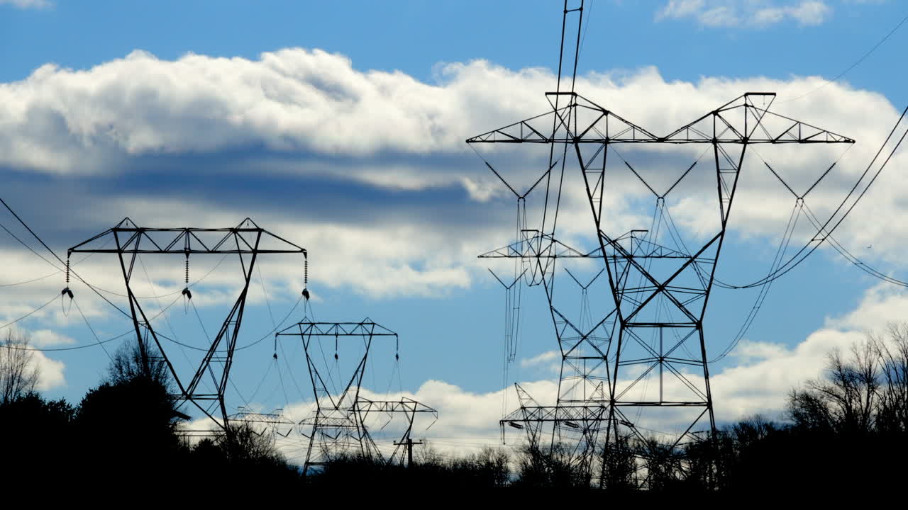 Electrical towers and swaying transmission lines with clouds moving in time-lapse motion