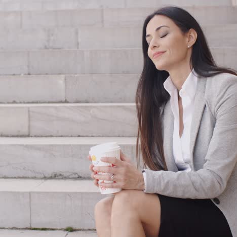 grinning woman on stairs drinking coffee