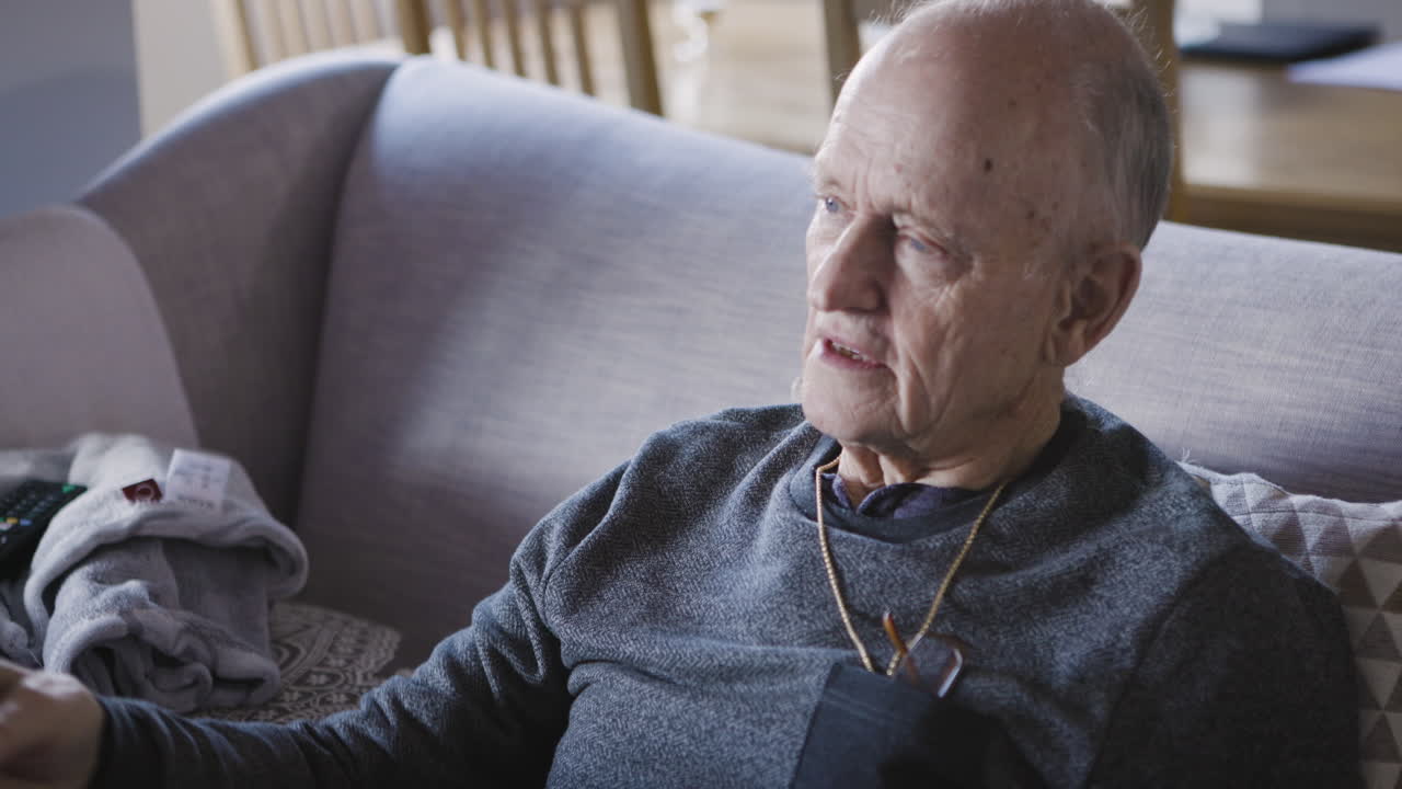 Elderly man sitting on sofa at home