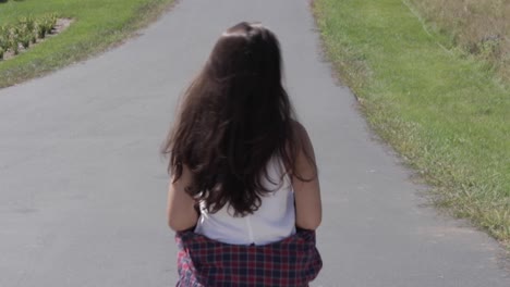 Close-up-Shot-Of-A-Young-Woman-Walking-Down-The-Side-Of-A-Rural-Road