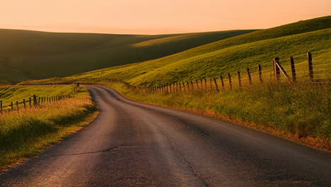 winding country road through green hills at sunset