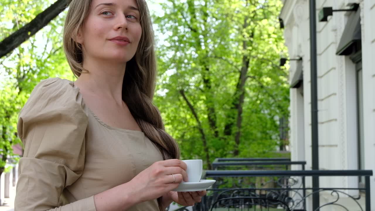 Woman in brown dress drinking coffee outside